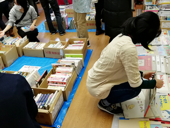 本のリサイクル市で真剣に絵本を選ぶお母さん